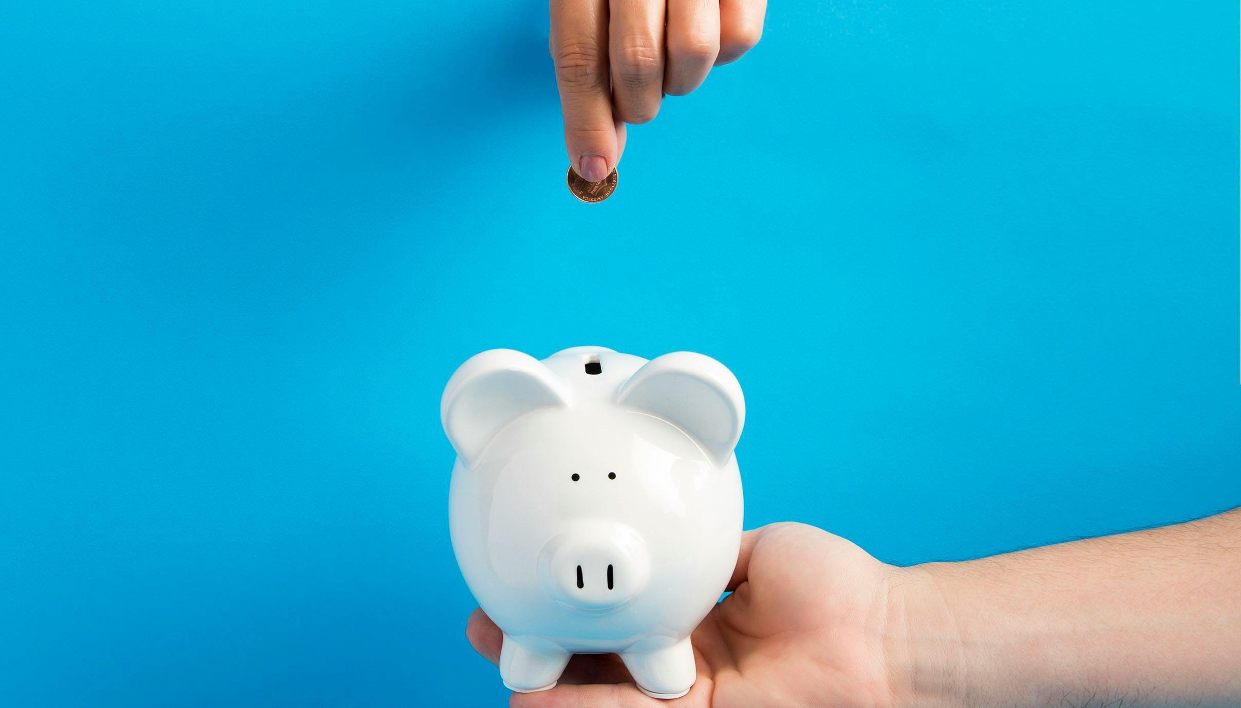 Coins being placed into a piggy bank